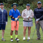 Four golfers smiling on the green at the Towboat Golf Classic.